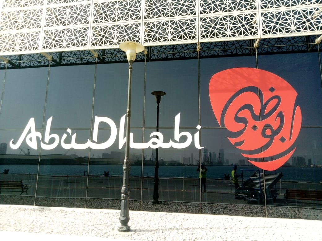 Abu Dhabi script wall sign with red identity mark