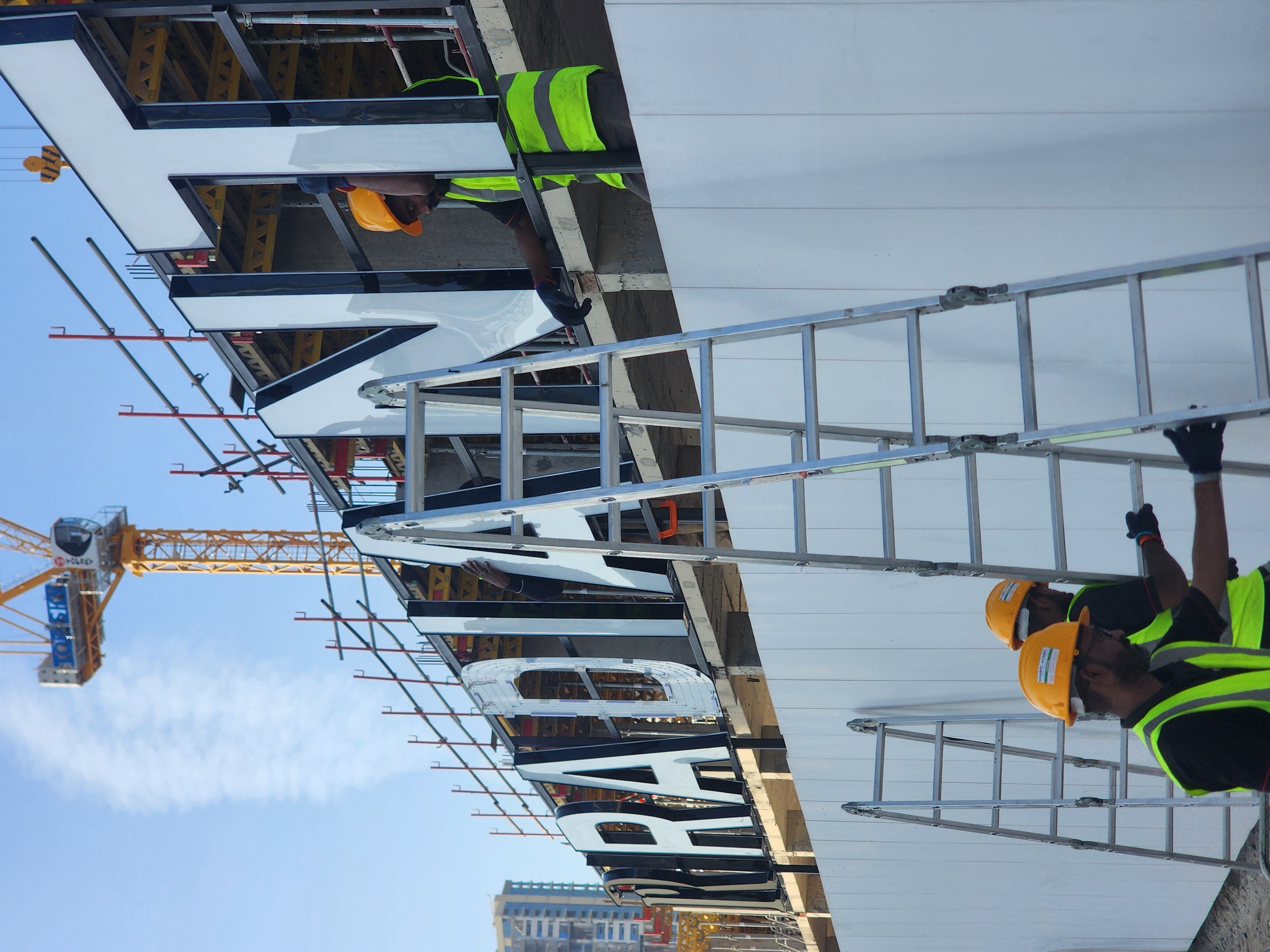 Close view of large facade letters being fixed during installation
