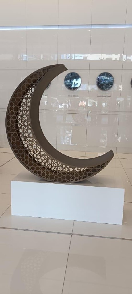 Geometric crescent moon sculpture on white pedestal in lobby