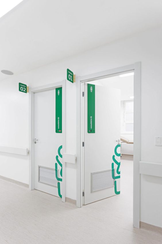Green exit and door safety signs on white doors