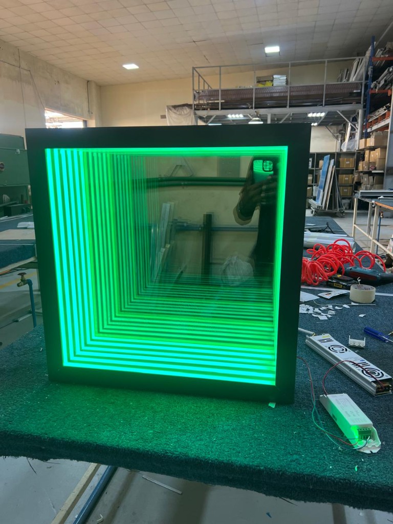 Square infinity mirror with green LED lighting on workbench