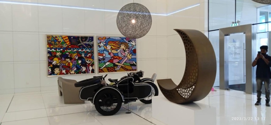 Lobby installation with pop art panels, motorcycle and crescent sculpture