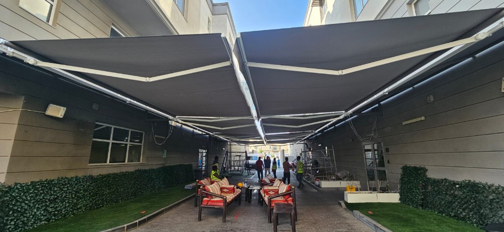 Wide view of retractable awning system across a courtyard