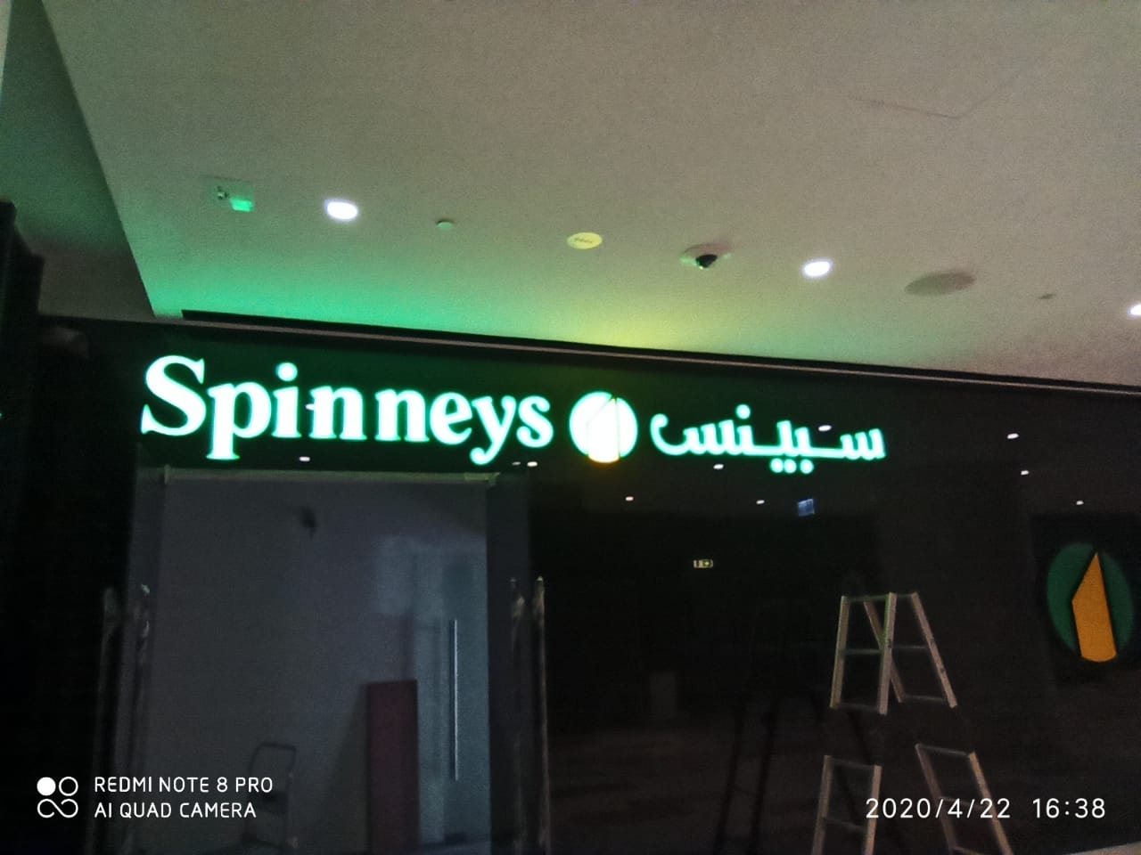 Illuminated Spinneys storefront sign in English and Arabic