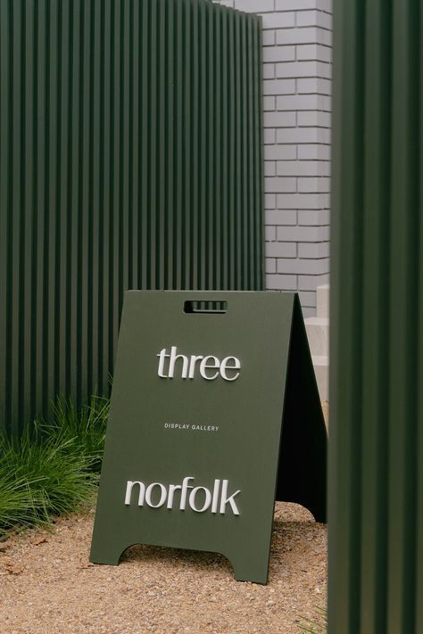 Three Norfolk pylon sign beside green wall