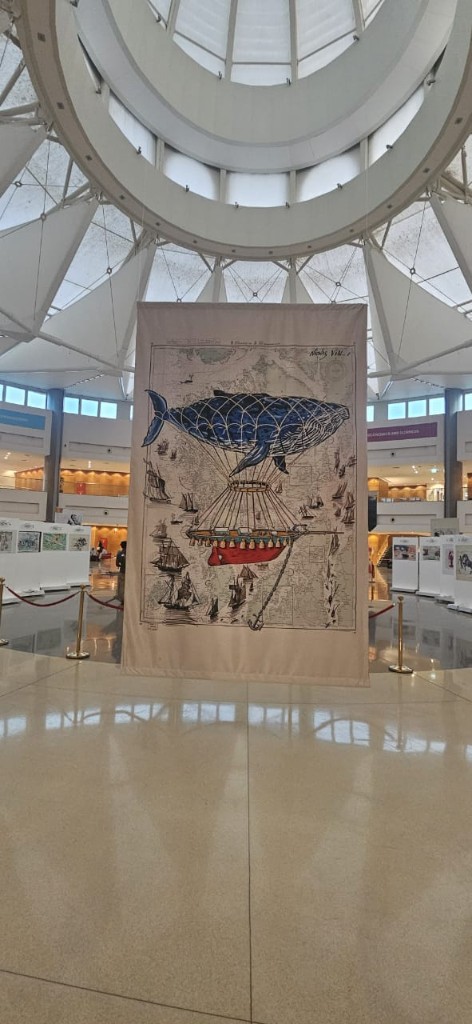 Large whale airship illustration on hanging fabric banner in atrium